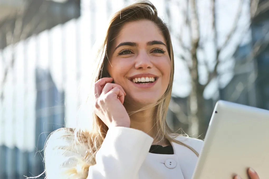 A woman holding a tablet and talking on the phone.